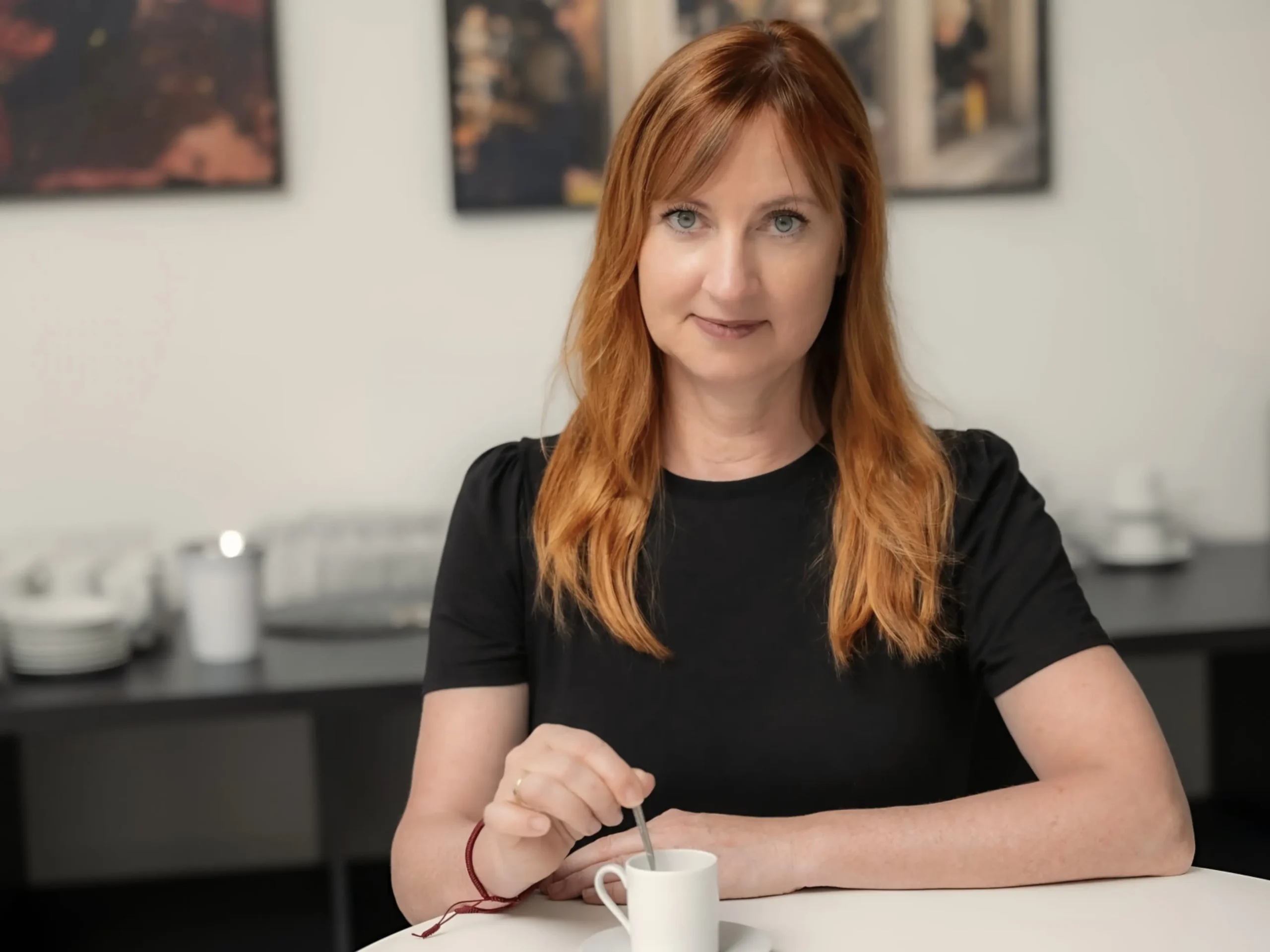 Schwarzweiß-Porträt der Autorin Katharina Dauer an einem Tisch mit Espressotasse